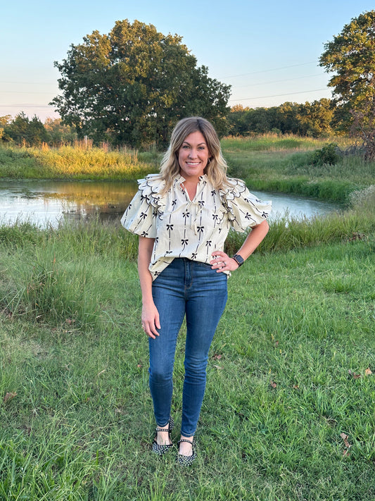 Bow print short puff sleeve v-neck top w/ tiered scallop delay at shoulders. Ruffle neckline